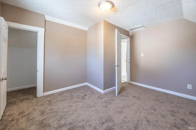 unfurnished bedroom with carpet, vaulted ceiling, and a textured ceiling