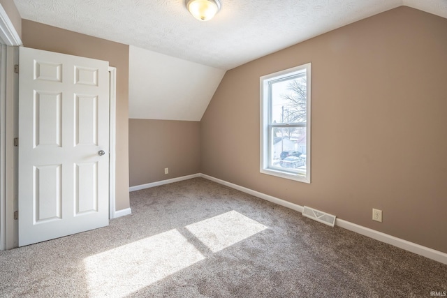 bonus room with a textured ceiling, vaulted ceiling, and carpet floors