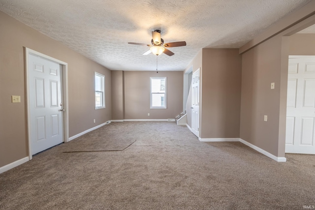 carpeted empty room with ceiling fan and a textured ceiling