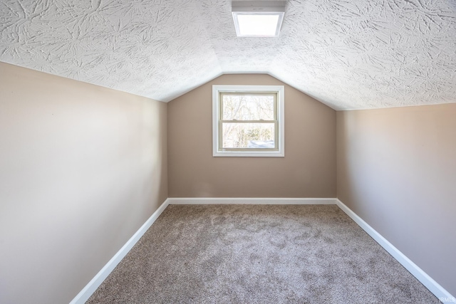 additional living space with carpet, a textured ceiling, and lofted ceiling