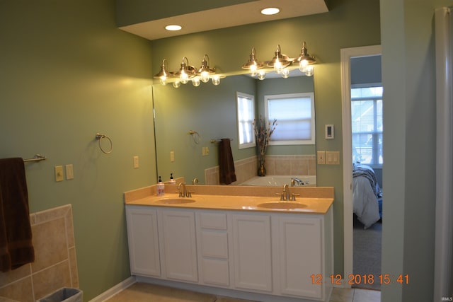 bathroom with ensuite bathroom, double vanity, a sink, and recessed lighting