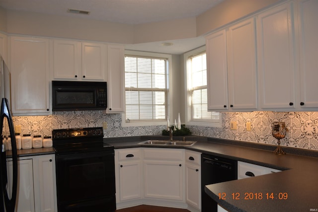 kitchen featuring black appliances, dark countertops, a sink, and white cabinetry