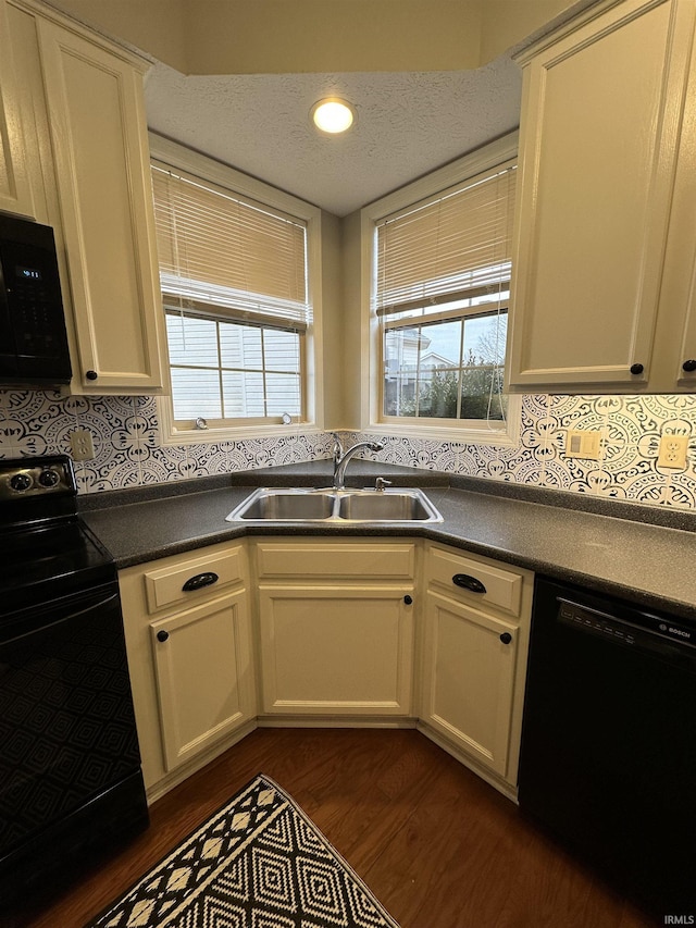 kitchen with a textured ceiling, dark wood-style flooring, a sink, black appliances, and dark countertops