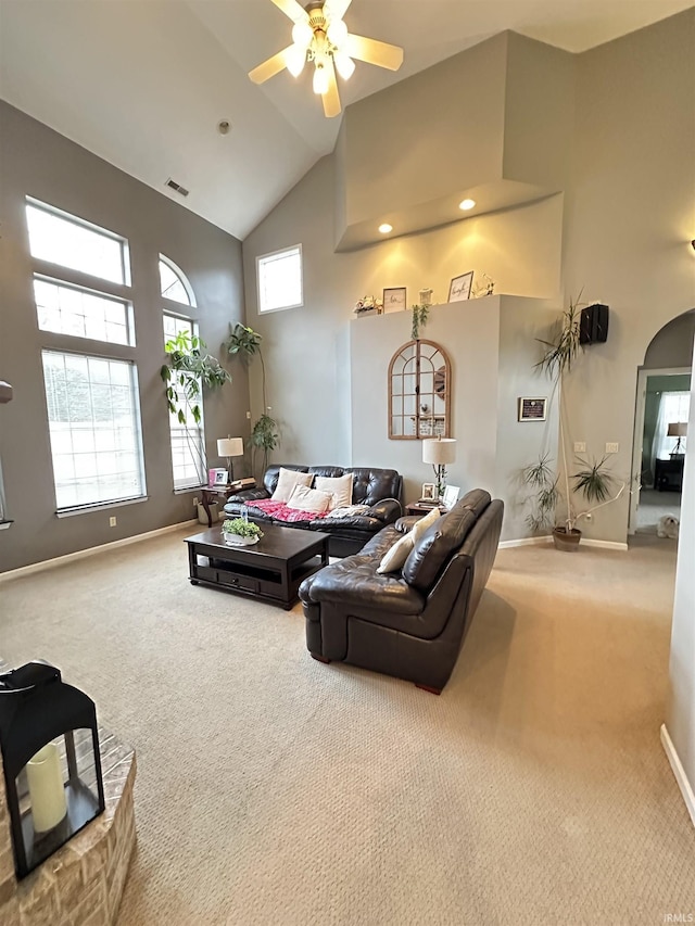 living room with high vaulted ceiling, arched walkways, visible vents, and carpet