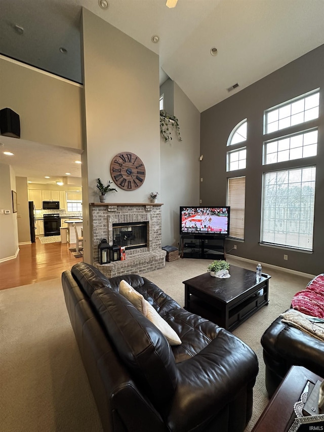 living area with visible vents, a fireplace, and a high ceiling