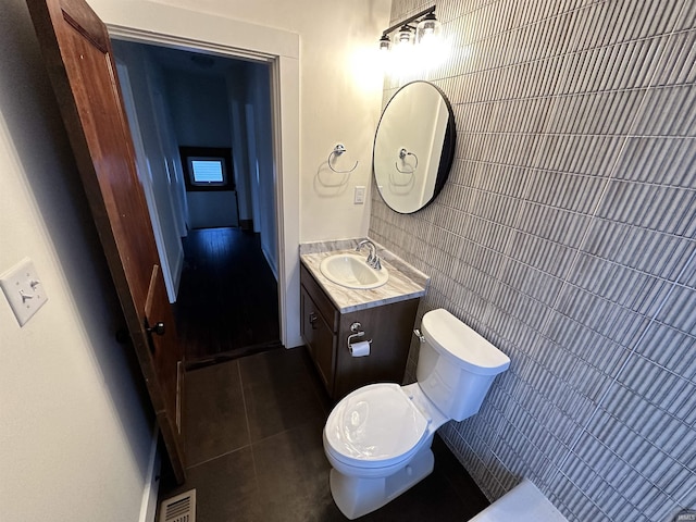 bathroom featuring tile walls, visible vents, toilet, vanity, and tile patterned floors