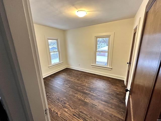 unfurnished bedroom with dark wood-type flooring, multiple windows, and baseboards