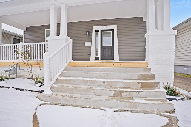 snow covered property entrance with a porch