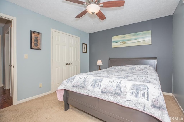 bedroom with light carpet, a closet, ceiling fan, and a textured ceiling