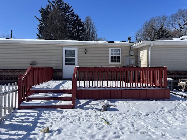 snow covered house with a deck and cooling unit