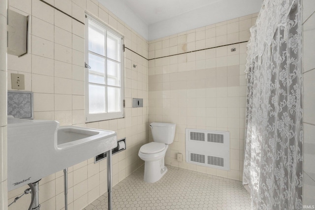 bathroom with tile patterned flooring, toilet, radiator heating unit, a shower with curtain, and tile walls