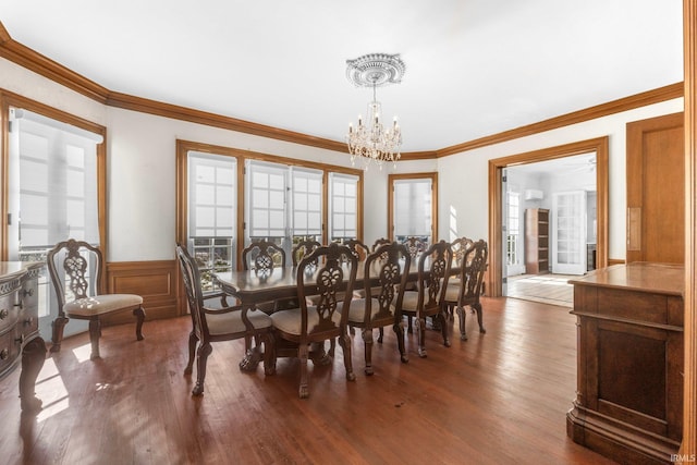 dining area featuring dark wood-type flooring, a notable chandelier, and ornamental molding