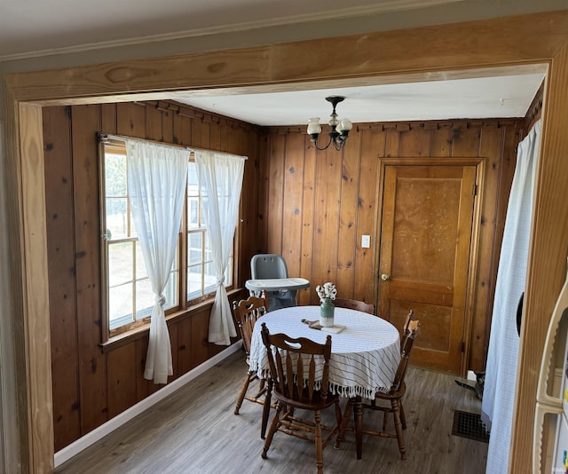 dining room with beam ceiling, an inviting chandelier, and hardwood / wood-style floors