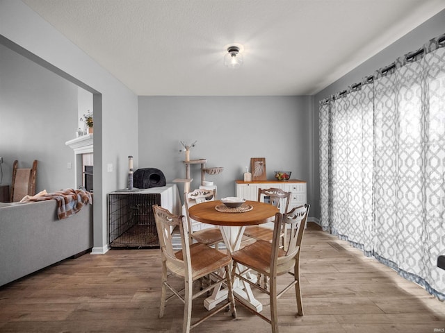 dining space featuring light wood-type flooring and a textured ceiling