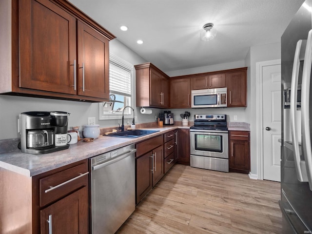 kitchen featuring appliances with stainless steel finishes, sink, and light hardwood / wood-style floors