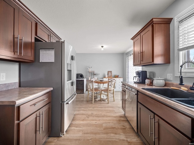 kitchen with sink, stainless steel appliances, and light hardwood / wood-style floors