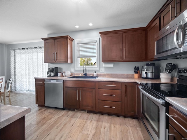 kitchen with sink, appliances with stainless steel finishes, and light hardwood / wood-style floors