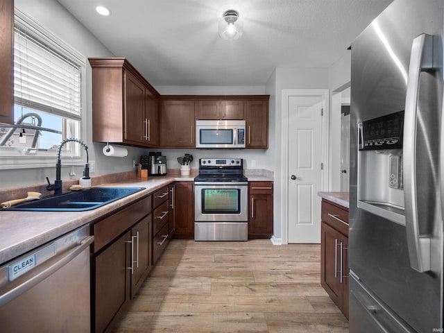 kitchen with sink, stainless steel appliances, dark brown cabinetry, and light hardwood / wood-style floors