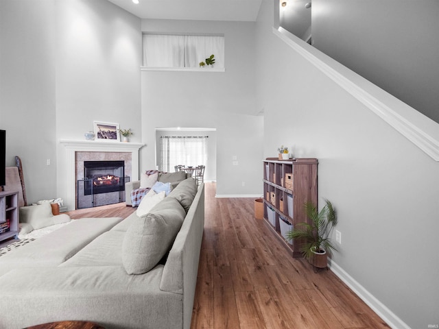 living room featuring a fireplace, hardwood / wood-style flooring, and a towering ceiling