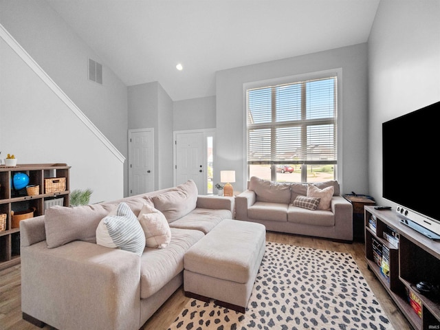 living room with high vaulted ceiling and light wood-type flooring