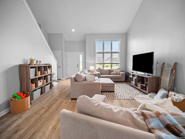 living room with high vaulted ceiling and light hardwood / wood-style flooring