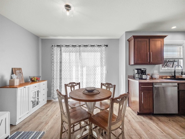 kitchen featuring dark brown cabinetry, light wood-type flooring, sink, and stainless steel dishwasher