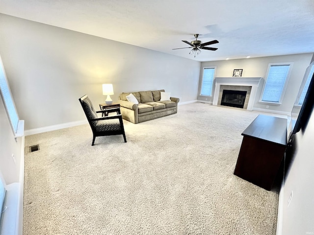 living room featuring ceiling fan, a tile fireplace, carpet, and a healthy amount of sunlight