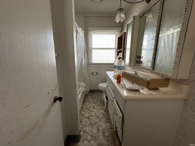 bathroom with toilet, tile walls, and vanity