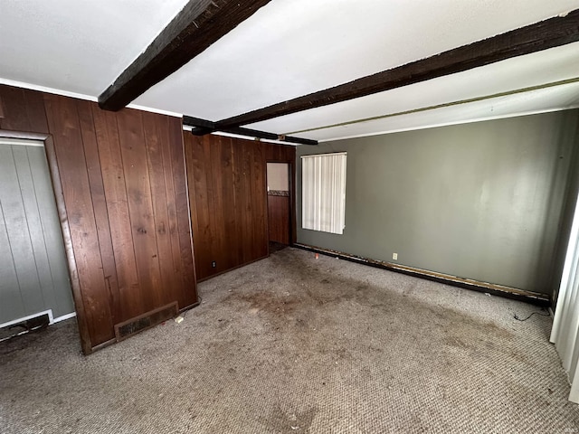 interior space with carpet, beamed ceiling, and wooden walls