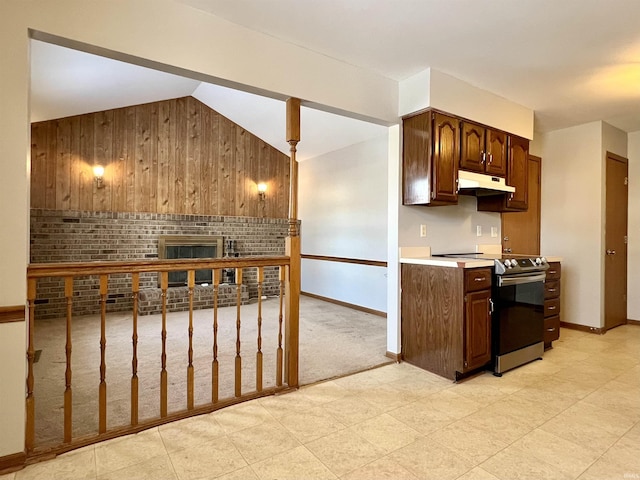 kitchen with vaulted ceiling, stainless steel range with electric cooktop, wooden walls, and dark brown cabinetry