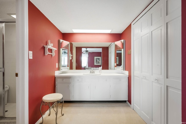 bathroom with ceiling fan, vanity, and a skylight