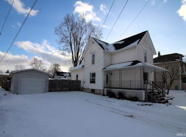 view of snow covered exterior featuring covered porch, an outdoor structure, and a garage