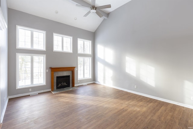 unfurnished living room featuring beam ceiling, wood-type flooring, a tiled fireplace, ceiling fan, and high vaulted ceiling