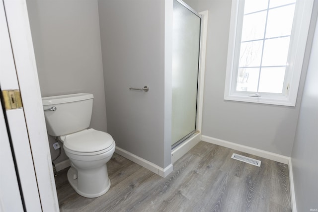 bathroom with hardwood / wood-style flooring, toilet, and a shower with shower door