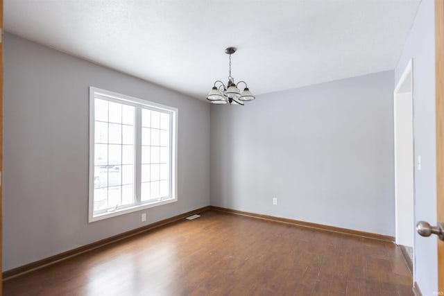 unfurnished room featuring a notable chandelier and dark hardwood / wood-style floors