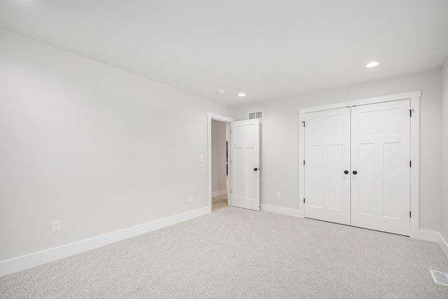 unfurnished bedroom with a closet and light colored carpet