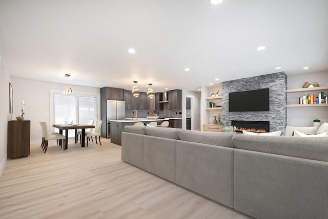 living room with sink, a stone fireplace, and light hardwood / wood-style flooring