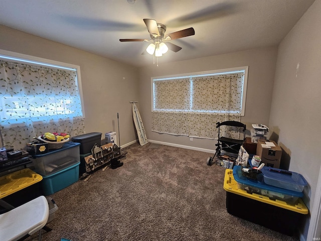 rec room with ceiling fan and dark colored carpet