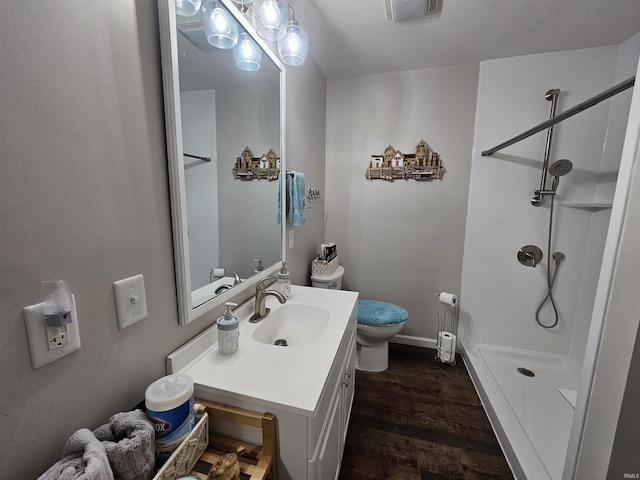 bathroom featuring toilet, hardwood / wood-style flooring, walk in shower, and vanity