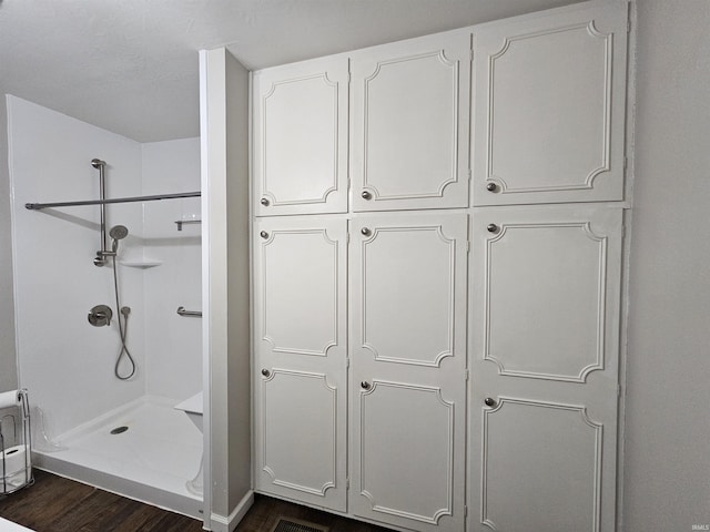 bathroom with hardwood / wood-style flooring and walk in shower