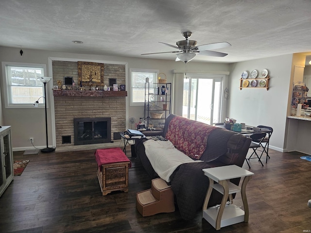 living room featuring a fireplace, dark wood-type flooring, a textured ceiling, and ceiling fan