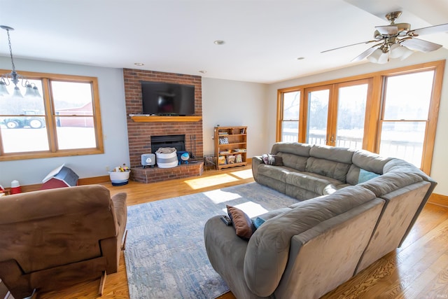 living room featuring ceiling fan, a brick fireplace, and light hardwood / wood-style floors