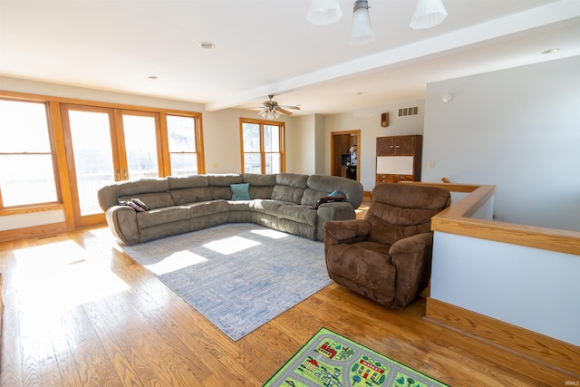 living room with beam ceiling, ceiling fan, light wood-type flooring, and french doors