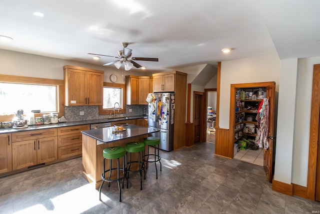 kitchen featuring a breakfast bar, a kitchen island, sink, appliances with stainless steel finishes, and decorative backsplash