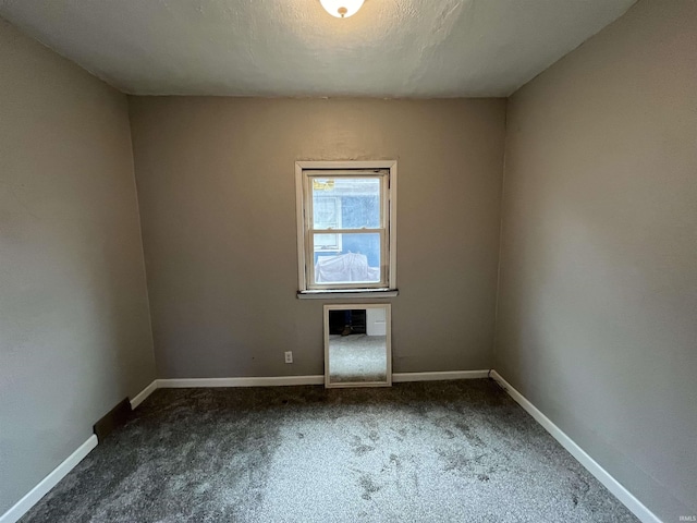 spare room with dark colored carpet and a textured ceiling