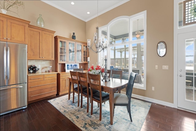 dining area with a high ceiling, ornamental molding, dark hardwood / wood-style floors, and a healthy amount of sunlight