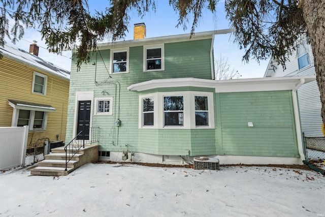 back of house with a chimney, central AC, and fence