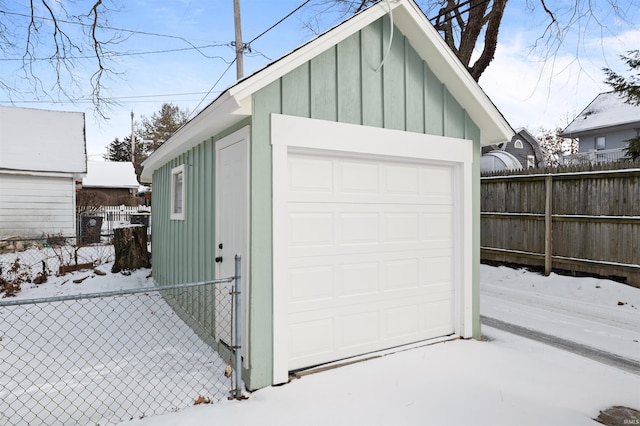 snow covered garage with fence and a garage