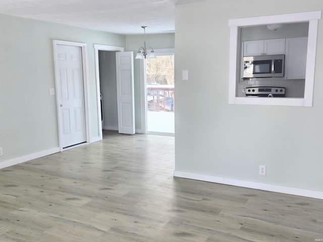 unfurnished room with hardwood / wood-style flooring and a notable chandelier