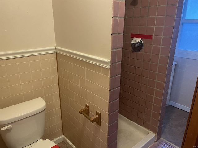 bathroom with tile walls, tiled shower, and toilet